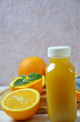 Fototapeta na wymiar Bottle of orange juice studio shot orange organic freshly squeezed juice in a small plastic bottle on a colorful background next to sliced orange and a mint leaves