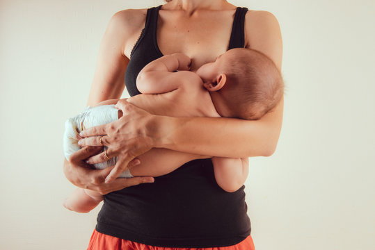 Happy mother with newborn baby infant on hands standing and breasfeeding lacting lactation health and care bonding time