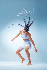 Attractive excited fitness girl dancer in sportwear. Wild dance isolated over blue background....