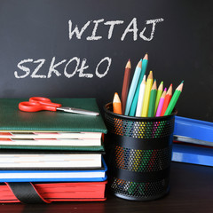 Szkolna tablica, kredki i zeszyty. Napis: Witaj Szkoło © shake_pl