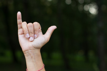 signs and symbols for people with disabilities mute and deaf humans concept of dactyl alphabet by female hand and fingers with empty space for copy or text on unfocused dark background