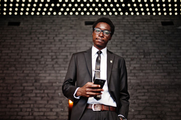 Business african american man wear on black suit and glasses at office looking on mobile phone...