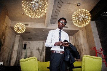 Business african american man wear on black suit and glasses at office looking on mobile phone.