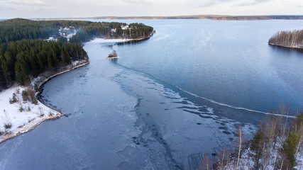 Aerial view of partially frozen lake and forest on cold winter day, northern Karelia, Russia