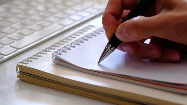 Female hand writing a word &ldquo;ideas&rdquo; in the notebook