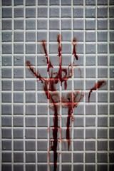 Old and dried out bloody handprint or bloodstains with streaks on wet bathroom tiles wall. Horror...