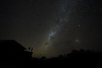 Naklejka premium Couple on rooftop watching mliky way and stars in the night sky on Bali island