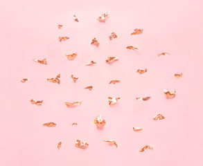 Golden elements and crumbs foil on pastel pink paper background.