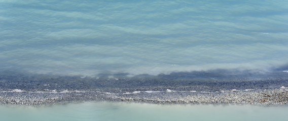 background - shore edge of tailing pond of soda plant with turquoise water