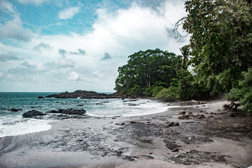 Empty beach in a rocky bay with black sand on the coast of Puntaarenas province in Costa Rica, near Montezuma