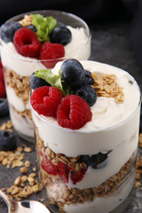 Glass jar of homemade granola with yogurt and fresh berries