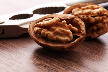 Walnut kernels and whole walnuts on brown wooden table.