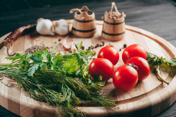 Spices: chili, black pepper, garlic, cumin, coriander, sweet pepper lie on a brown round wooden board on a black table. Place under the text.
