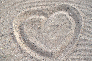 The symbol of love is a heart drawn on the sand of the sea beach.