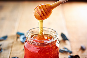 Glass jar full with honey and wooden spoon