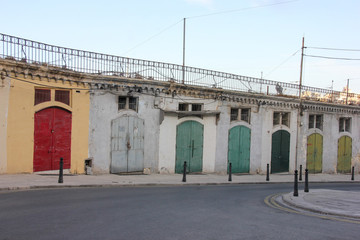 Colorful doors of storages in empty street of Malta near port