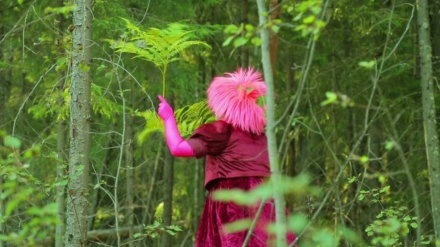The laughing witch in the forest glade is dancing with the branches of the fern.