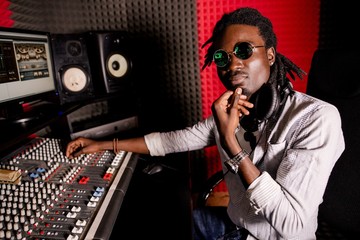 African male adjusts music to sound mixer for recording, broadcasting, background music - Powered by Adobe