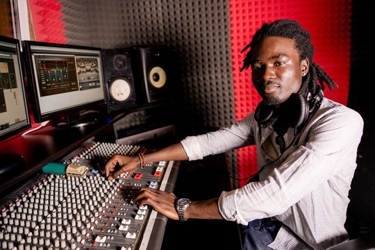 African musician with dreadlocks creates sound on the mixing console