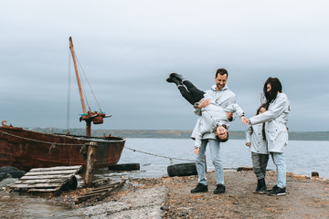 Family running and have a fun near the sea in raincoat