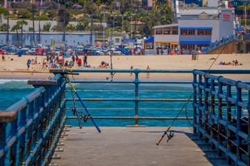 Outdoor view of fishing rods standing in a wooden pier used for people that usually fishing in the pier of Santa Monica
