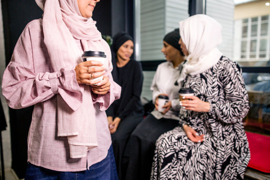 Four Muslim hijab women drinking coffee communicating with each other