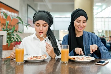 Muslim women in hijab have lunch in the cafe inside