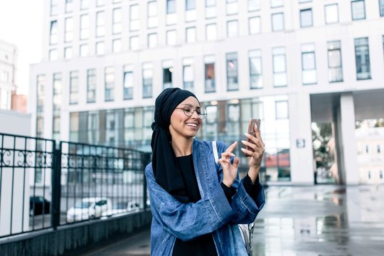 Muslim girl standing on the street typing on the phone
