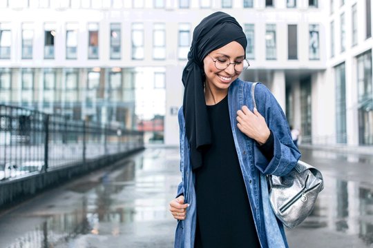 Muslim girl standing on a city street with a woman's bag