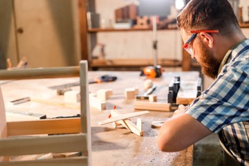 Bearded carpenter doing carpentry at the workplace