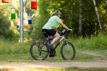 Fototapeta na wymiar Sports woman cycling in the park. Side view