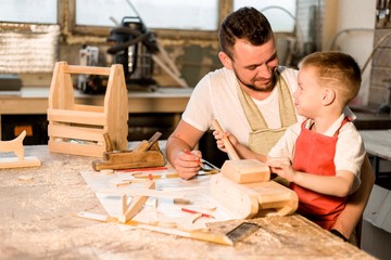 Dad and son in the carpenter's shop make wooden toys learning carpentry craft