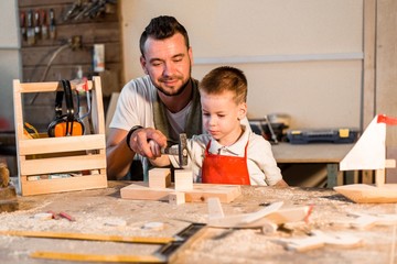 Dad teaches his son carpentry in the carpentry workshop