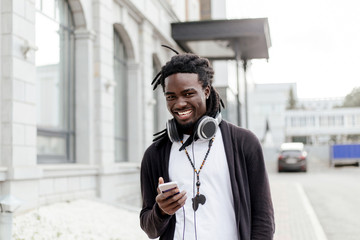 African man with dreadlocks walking down the street with headphones