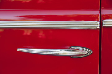detail of chrome handle and strip on vintage red car door