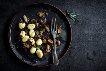 Prepared mushrooms and gnocchi dish in the plate with blank space for text,selective focus
