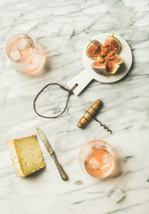 Fototapeta na wymiar Flat-lay of glass of rose wine with ice cubes, cheese and fresh figs over marble background. Summer wine and snack set, top view