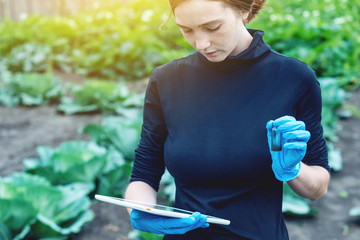 Agronomist woman holding a soil sample and a tablet. Environmentally friendly farm production