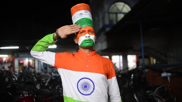 An Indian man with Indian flag tricolor face paint and tricolor shirt and salutes the camera on Indian Independence day and republic day, Slow motion