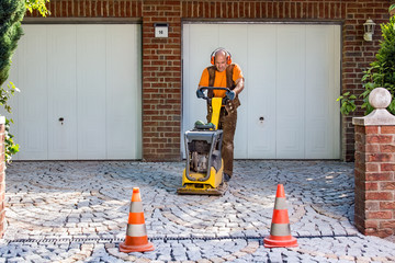 Builder or contractor laying new paving bricks.