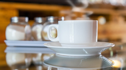 A cup of hot coffee in white cup with steaming in coffee shop.