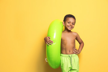 Cute African American boy with bright inflatable ring on color background