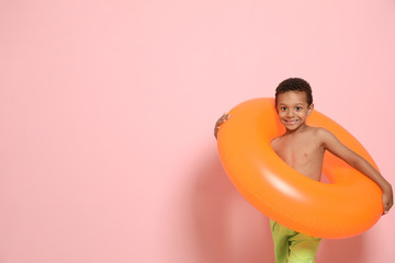 Fototapeta premium Cute African American boy with bright inflatable ring on color background