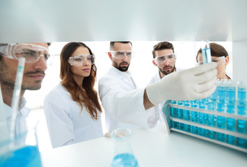 background image is a group of microbiologists studying the liquid in the glass tube.