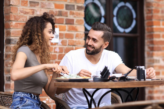 Young couple enjoying coffee at a street cafe and  laughing