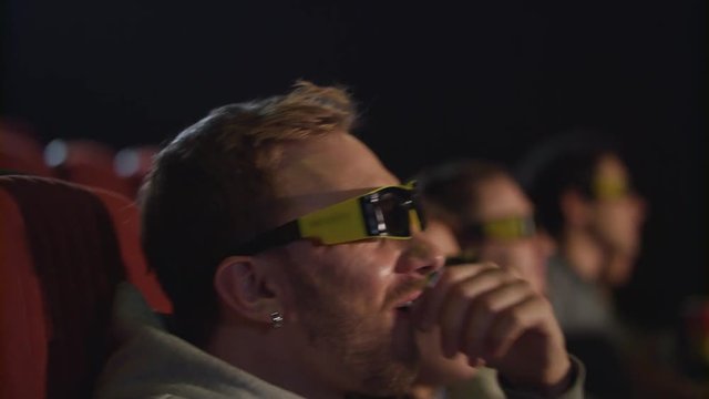 Close up of man in 3d glasses watching film. Man take off movie glasses in cinema in slow motion. Tired from 3d movie. 3d movie audience