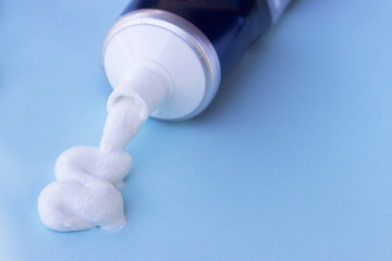 Toothpaste squeezed out from tube on blue background. Dental hygiene concept.