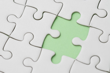 Business success strategy, problem, solution and answer metaphor concept, closed up of white jigsaw puzzle missing only one last piece to complete on pastel green background