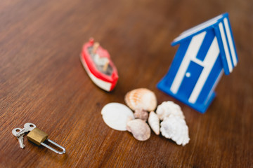 Padlock and keys of a beach house next to wooden toy house with maritime motives.