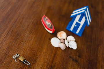 Padlock and keys of a beach house next to wooden toy house with maritime motives.